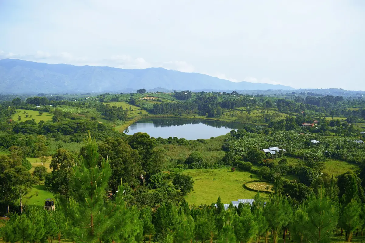 Crater lake among green hills with distant mountains near Fort Portal