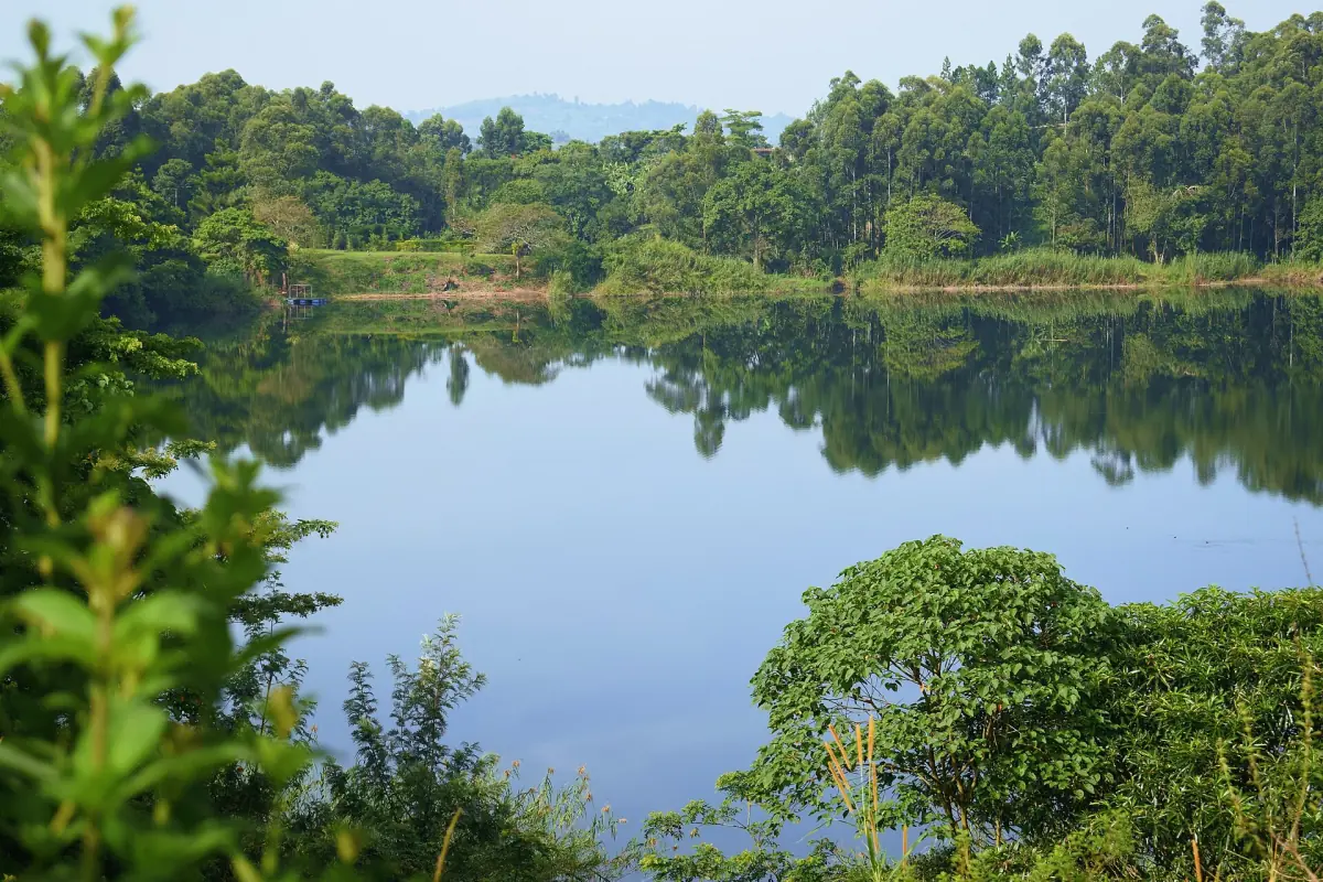 Calm crater lake ringed by forest with clear reflections near Fort Portal