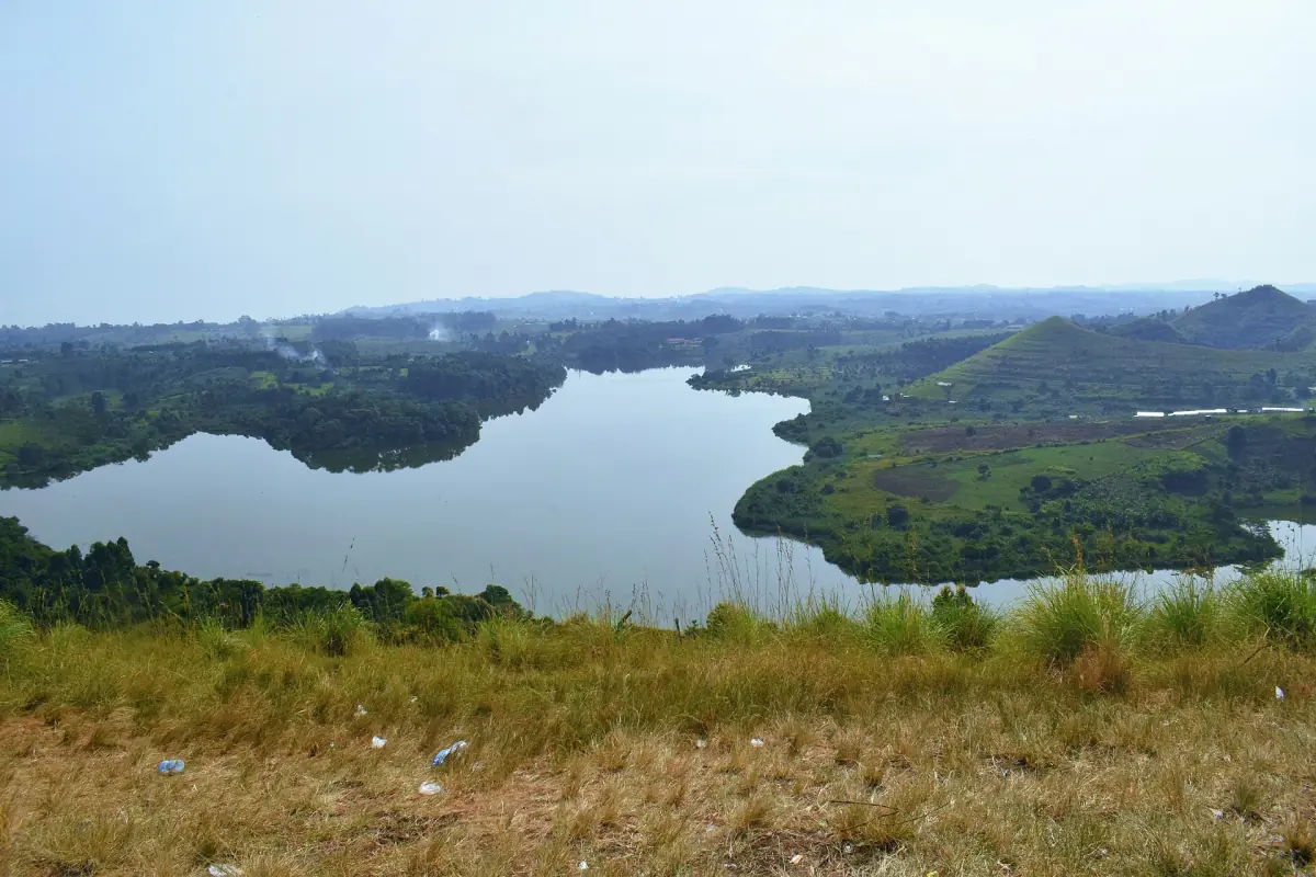Wide crater lake landscape with hills under a blue sky near Fort Portal