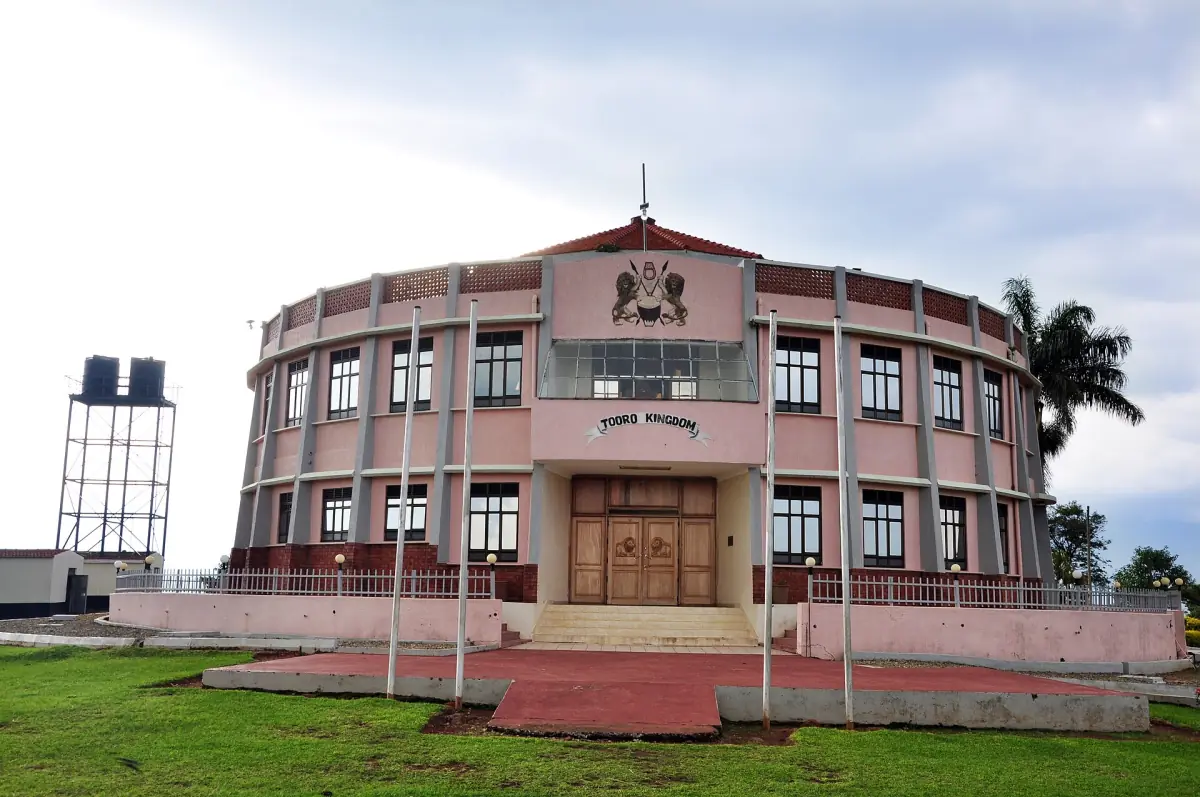 Front of the Tooro Palace with red entrance steps and a green lawn